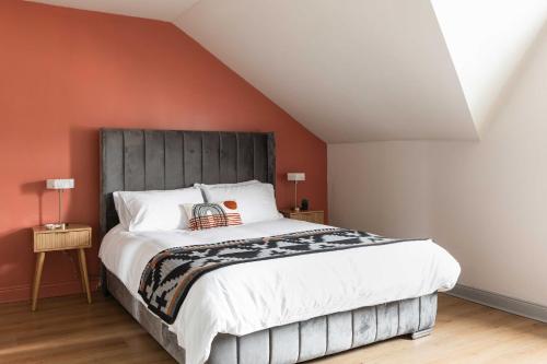 a bedroom with a large bed with an orange wall at 1BR-3BR Apartments in Bangor, Mins to Seafront & High St in Bangor