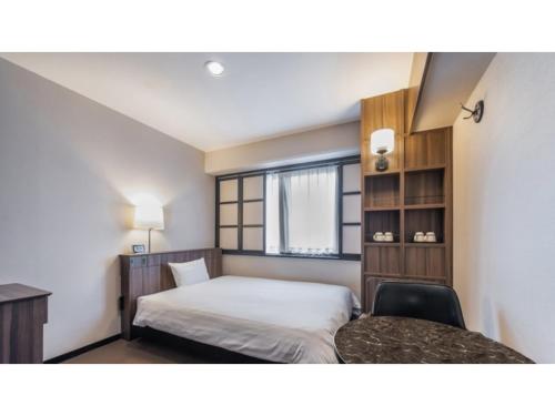 a bedroom with a bed and a desk and a window at Sun Hotel Fukuyama - Vacation STAY 53469v in Fukuyama