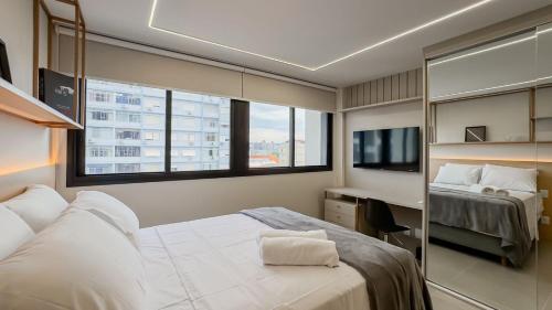 a bedroom with a bed and a desk and a tv at GO Rio Branco by LikeHome in Porto Alegre