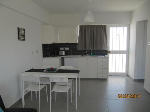 a white kitchen with a white table and chairs at Sunny Holiday Apartments in Protaras
