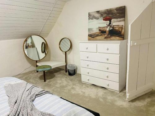 a bedroom with a white dresser and a mirror at The Olde Farmhouse 