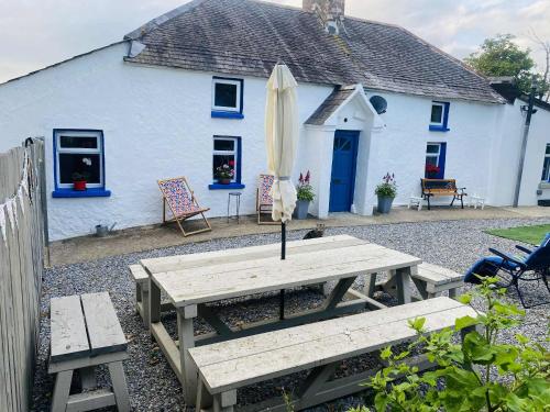 a white house with a picnic table and an umbrella at The Olde Farmhouse 