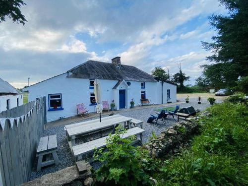 a white house with a picnic table and benches at The Olde Farmhouse 