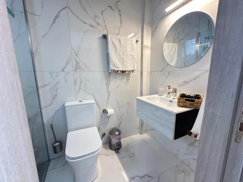 a white bathroom with a toilet and a sink at Home For You - Holiday Apt Larnaca in Larnaka