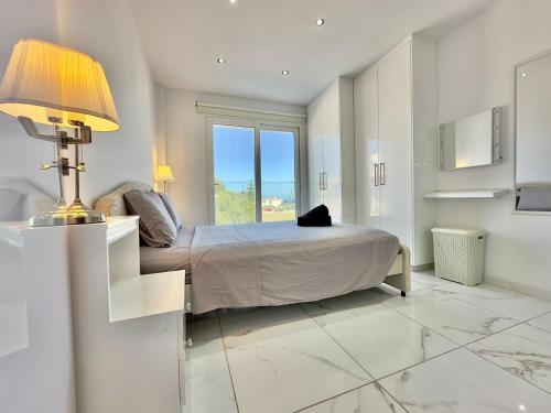 a bedroom with a bed with a lamp and a window at Lumière Retreat 2 in Larnaca
