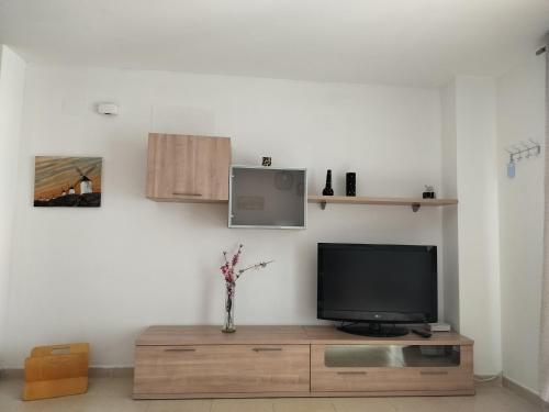 a living room with a television on a wooden cabinet at Apartamento en playa de Moncofar con wifi y aire acondicionado in Moncófar