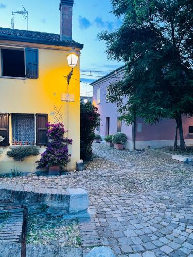 a yellow and pink house with a cobblestone street at Piccolo Da Vinci 17 in Cesenatico