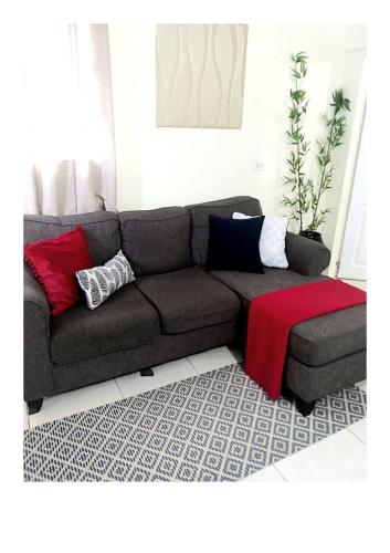 a living room with a brown couch with colorful pillows at The Hibiscus Retreat in Arima