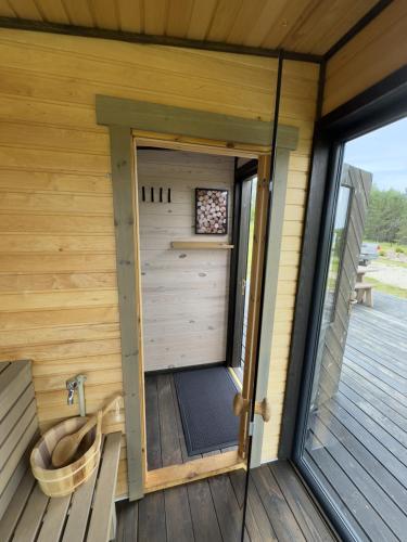 a door to a sauna with a tub on a deck at Melnā kalna kamene in Vestiena