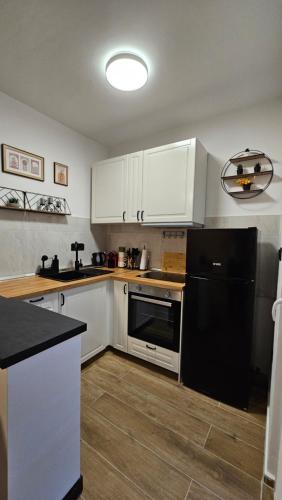 a kitchen with white cabinets and a black refrigerator at Val Center in Novalja