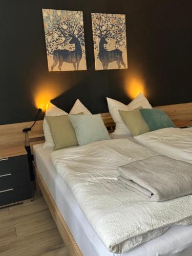 a bedroom with a bed with white sheets and deer paintings at ZwoLu Apartments in Bornheim