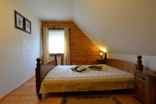 a bedroom with a bed with a wooden wall at Sodyba Tarp Liepų in Leliūnai