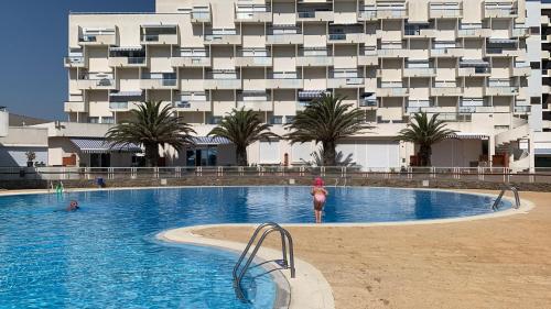 une femme debout dans une piscine en face d'un bâtiment dans l'établissement Les pieds dans l eau au Lydia Playa, au Barcarès