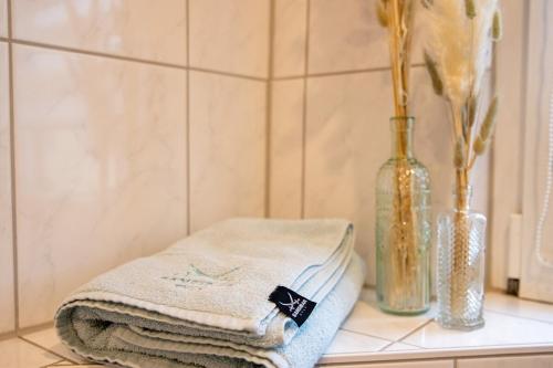 een badkamermeubel met drie handdoeken en een vaas bij Wohnung Pinot in Seenähe in Friedrichshafen