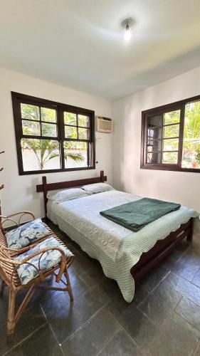 a bedroom with a bed and a chair and windows at Suites Palmar - Praia da Biscaia in Angra dos Reis