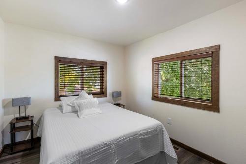 a white bedroom with a bed and two windows at Lakefront Washington Home with Private Pool and Sauna in Moses Lake