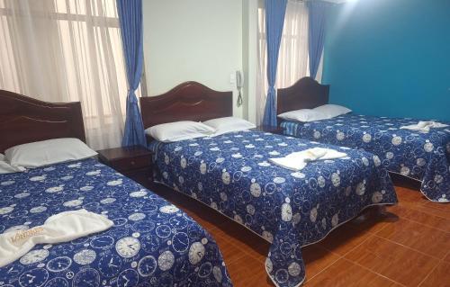 a room with two beds with blue and white blankets at Hotel Londres in Pasto