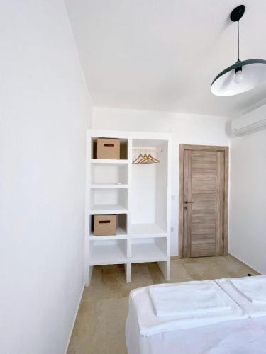 a bedroom with white walls and a bed and shelves at Çam Tatil Evleri in Datca