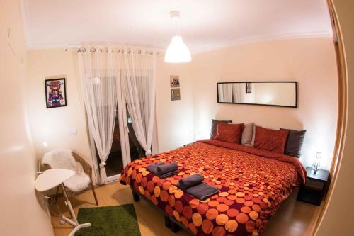een slaapkamer met een groot bed en een oranje dekbed bij Apartments Baleal: Close to the Sea + Pool in Baleal