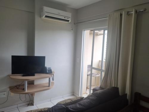 a living room with a couch and a tv and a window at Golden Dolphin Express Caldas Novas 309 in Caldas Novas