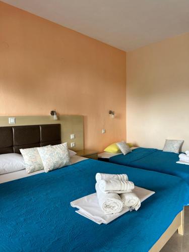 two beds in a hotel room with towels on them at Sissy's Suites San Antonio Beach Potos Thassos in Potos