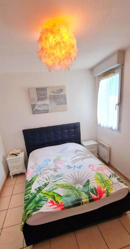 une chambre avec un lit et un lustre dans l'établissement Appartement lumineux avec piscine à St Estève, à Saint-Estève