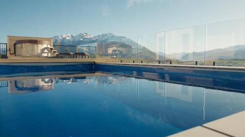 a pool of water with mountains in the background at Luxury Architectural Home with Pool, Spa and Sauna in Queenstown Airport