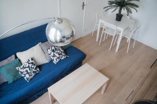 un salon avec un canapé bleu et une table dans l'établissement Séjour famille ou pro accès rapide St-Lazare, à Argenteuil