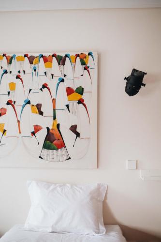 a painting hanging on a wall next to a bed at Douro Riverfront 2BR with Private Terrace & Garage in Porto