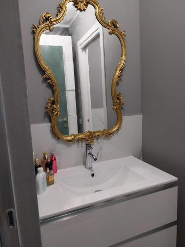 a bathroom sink with a gold framed mirror over it at Queen apartment in Ravenna