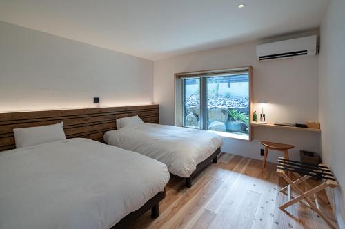 two beds in a room with a window at Sou in Isahaya