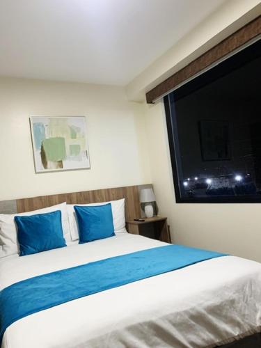 a bedroom with a bed with blue pillows and a tv at Hotel Suites La Fontana in Ambato