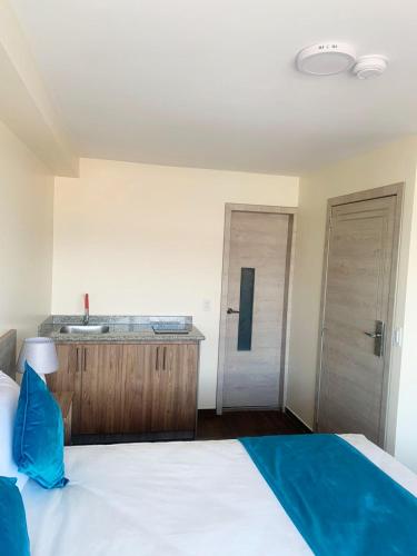a bedroom with a white bed and a sink at Hotel Suites La Fontana in Ambato