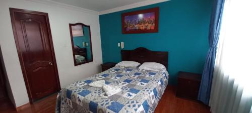 a bedroom with a bed with a blue wall at Hotel Londres in Pasto