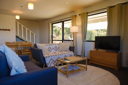 a living room with a couch and a tv at Treetops in Blenheim