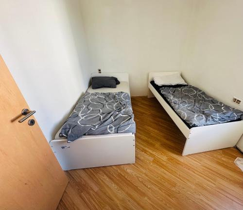 two beds in a small room with wooden floors at Privatzimmer Mama in Tresdorf