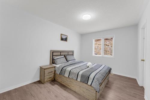 a white bedroom with a bed and a window at Spacious 5-Bedroom Family Home in GTA in Milton