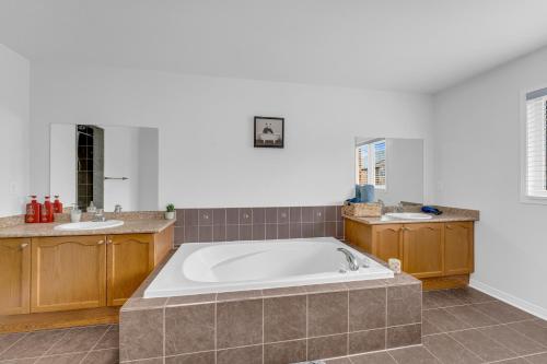 a large bathroom with a tub and two sinks at Spacious 5-Bedroom Family Home in GTA in Milton
