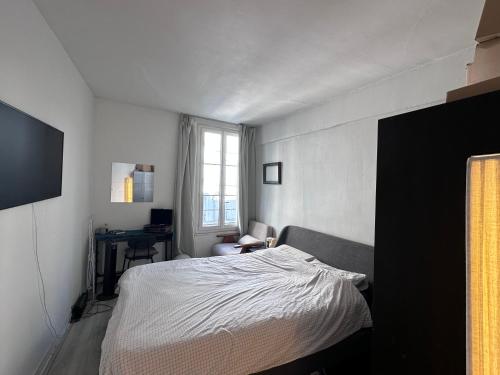 une chambre avec un lit, un bureau et une fenêtre dans l'établissement City Center, cute cozy Appart, à Paris