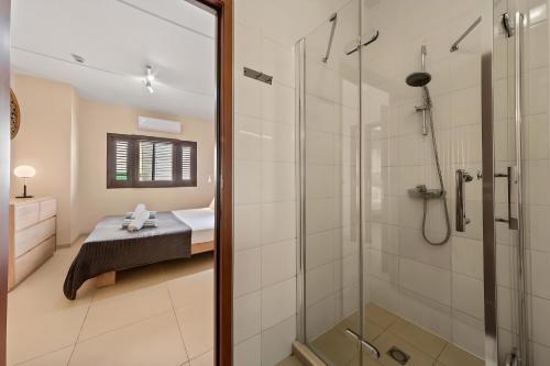 Un baño con ducha y una cama en una habitación. en Villa Devries C4 Jan Thiel Private Beachfront Pool, en Willemstad