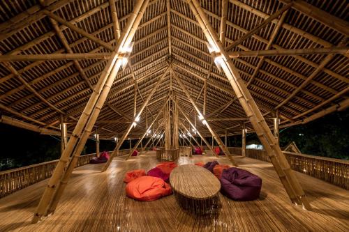 a wooden floor with a large roof with a table at Ecolodge Bukit Lawang in Bukit Lawang