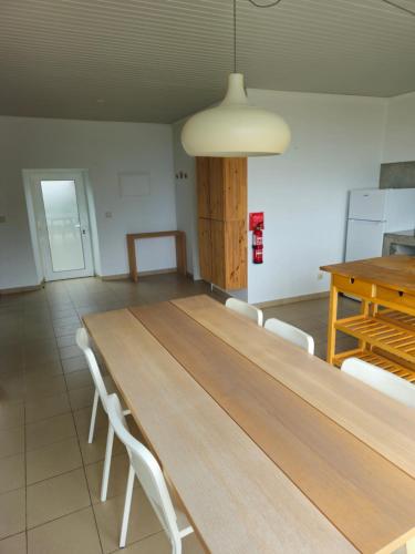 a large wooden table in a room with white chairs at Residências Requinte I in São Roque do Pico