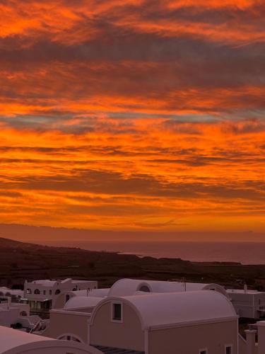 a sunset over a group of buildings with a cloudy sky at Acrothea Suites and Villas - Akrotiri Caldera - Santorini in Akrotiri