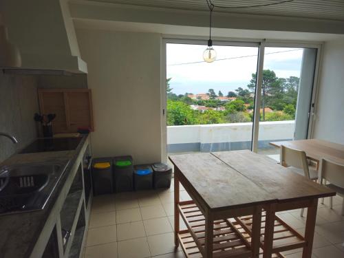 a kitchen with a table and a view of a balcony at Residências Requinte I in São Roque do Pico