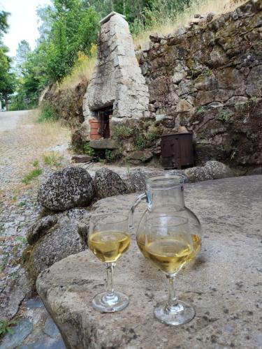 two glasses of white wine sitting on a stone table at Moinho do Zorrão in Manteigas