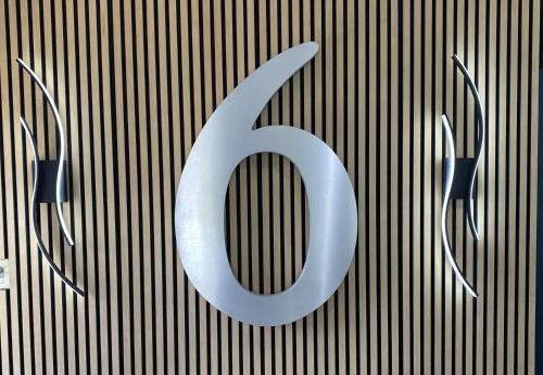 a large silver number on a wall with two speakers at Motel 6-Costa Mesa, CA in Costa Mesa