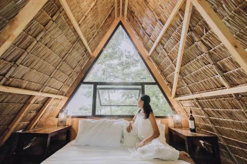 a woman sitting on a bed in a room with a large window at The Secret Hut in Cebu City