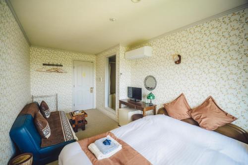 a bedroom with a bed and a chair and a television at 伊豆集 Episode IZU in Ito