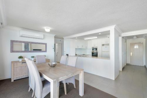 a kitchen and dining room with a wooden table and chairs at ULTIQA Beach Haven on Broadbeach in Gold Coast