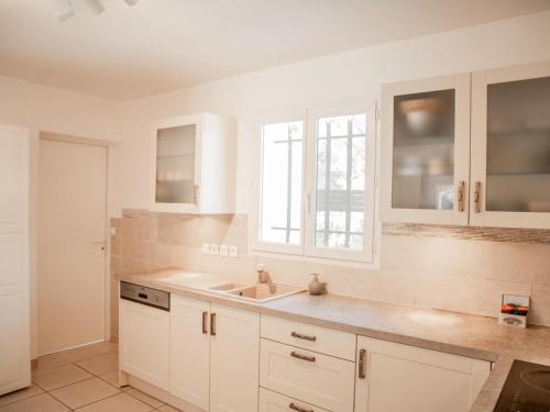 une cuisine avec des armoires blanches et un évier dans l'établissement La Noura, à Trans-en-Provence